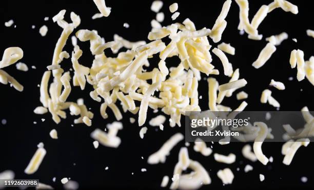 mozzarella cheese shred flying in mid air captured with high speed sync."n - shredded stockfoto's en -beelden