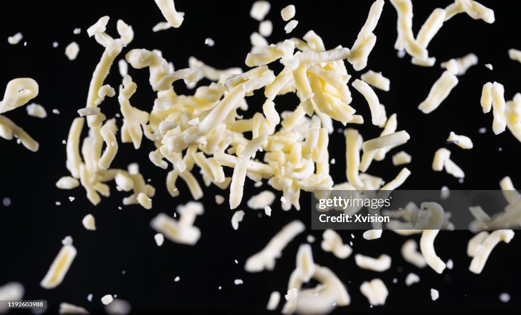 Mozzarella cheese shred flying in mid air captured with high speed sync."n