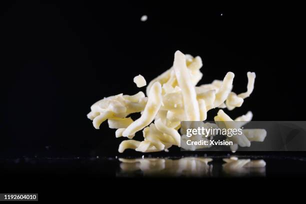 mozzarella cheese shred flying in mid air captured with high speed sync."n - super slow motion stock pictures, royalty-free photos & images