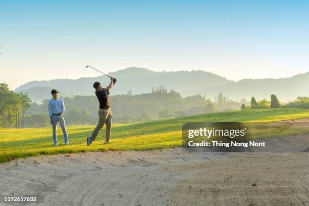 asian men playing golf on golf course - playing golf stock pictures, royalty-free photos & images