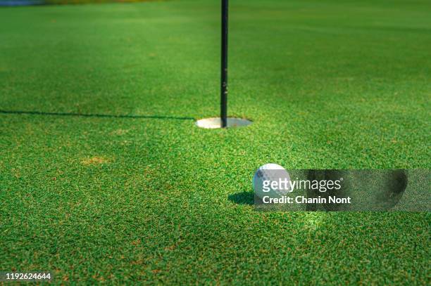golf flag and ball on the putting green - golfbaan green stockfoto's en -beelden