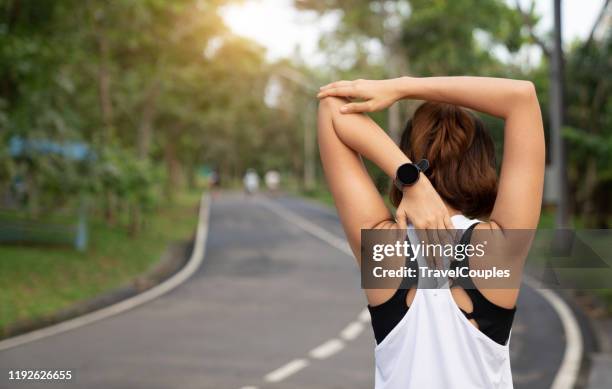 women stretching for warming up before running or working out. young female runner stretching arms before running at morning. fitness and healthy lifestyle concept. - rug handen zij stockfoto's en -beelden