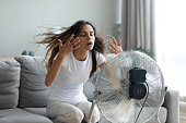Woman turned on fan waving her hands to cool herself