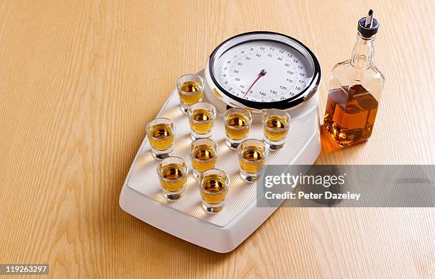 binge drinking on bathroom scales - comazuipen stockfoto's en -beelden