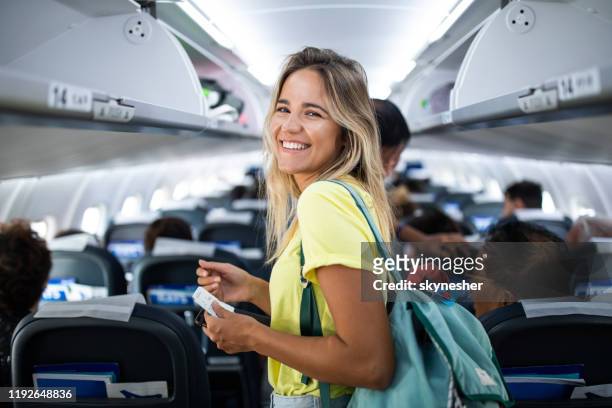 young happy woman in an airplane cabin. - air travel stock pictures, royalty-free photos & images