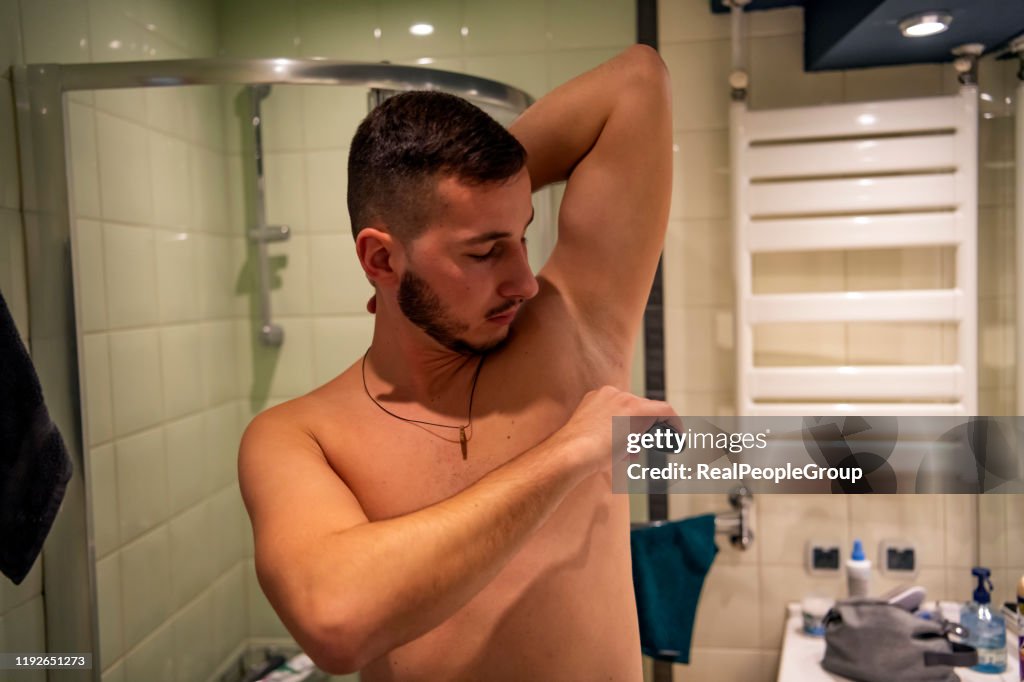 Ein hübscher junger Mann verwendet Deodorant im Badezimmer