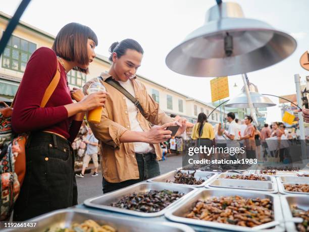 aziatische man het nemen van foto van gebakken insecten op straat eten. bangkok, thailand. - insekt stockfoto's en -beelden