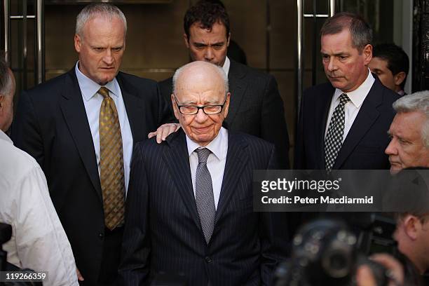 News Corp. Chairman Rupert Murdoch looks down as he leaves the One Aldwych Hotel surrounded by his personal security team to speak with reporters...