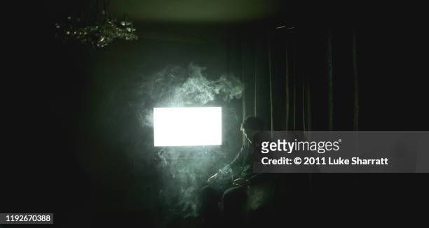 man sitting in dark room smoking - television set smoke stock pictures, royalty-free photos & images
