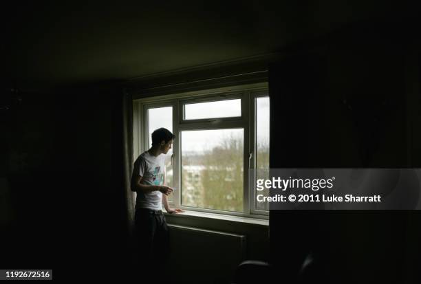 man smoking and staring out window - lonely man stockfoto's en -beelden