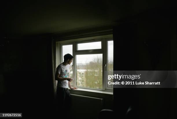 man smoking and staring out window - lonely man stock pictures, royalty-free photos & images