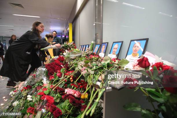 Woman leaves flowers at the portraits of nine crew members who were among 176 people on board of the Ukraine International Airlines Boeing 737 killed...