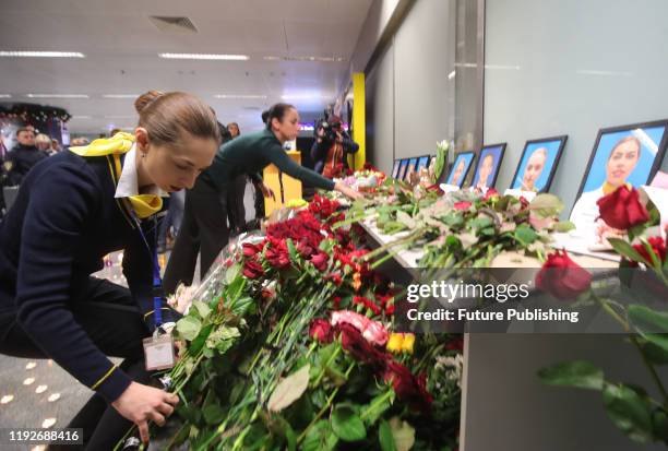 Employees of the Ukraine International Airlines arrange flowers at the portraits of nine crew members who were among 176 people on board of the UIA...