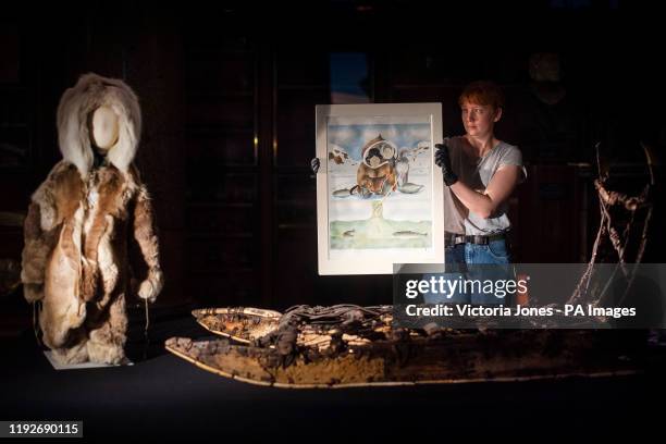 Staff member holds 'There's Another One' by Andrew Qappik 2012, alongside a child's suit made of caribou fur, and a North West Greenlandic Inughuit...