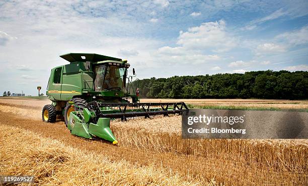 Farmer harvests winter wheat with a Deere & Co. John Deere tractor combine harvester in Kirkland, Illinois, U.S., on Thursday, July 14, 2011. Wheat...