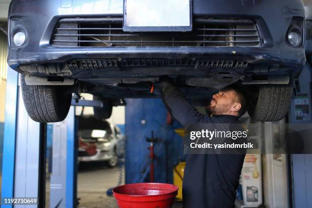 mecánico vaciando el aceite en un cubo. reparar coche - oil change fotografías e imágenes de stock