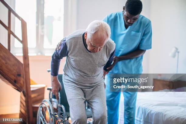 männliche krankenschwester und senior mann - rollstuhl schieben stock-fotos und bilder