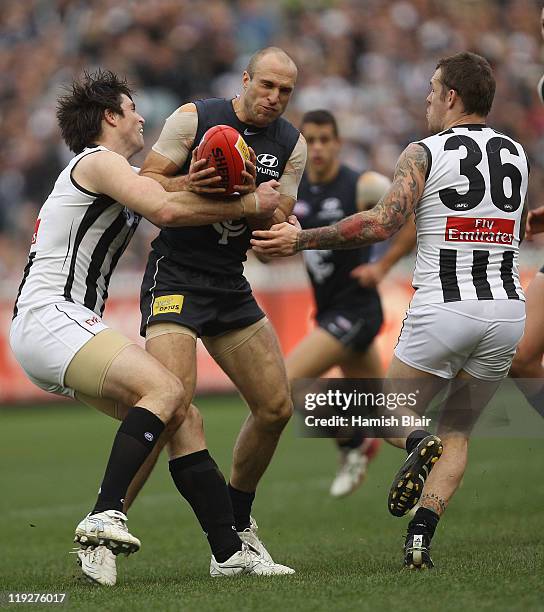 Chris Judd of the Blues is tackled by Leigh Brown and Dane Swan of the Magpies during the round 17 AFL match between the Carlton Blues and the...