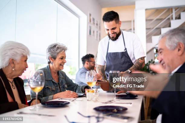 kellner serviert gericht für eine gruppe von kunden in einem restaurant - waiter serving stock-fotos und bilder