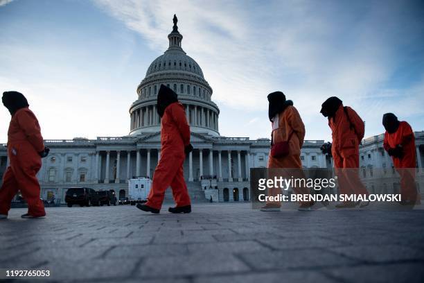 Demonstrators dressed in Guantanamo Bay prisoner uniforms march past Capitol Hill in Washington, DC, on January 9 during a rally on "No War with...