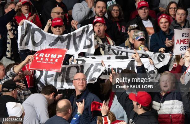 Protesters hold signs as US President Donald Trump holds a "Keep America Great" campaign rally at Huntington Center in Toledo, Ohio, on January 9,...