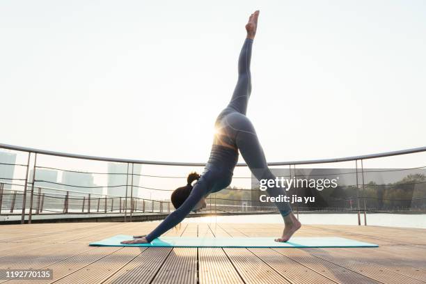 a young woman is practicing yoga. - sunrise yoga stock-fotos und bilder