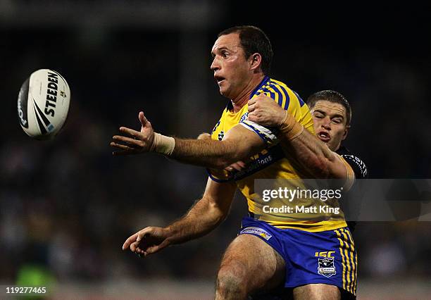 Luke Burt of the Eels gets a pass away in a tackle from Travis Burns of the Panthers during the round 19 NRL match between the Penrith Panthers and...