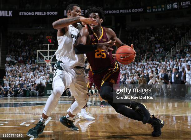 Daniel Oturu of the Minnesota Golden Gophers drives to the basket while defended by Xavier Tillman of the Michigan State Spartans in the second half...