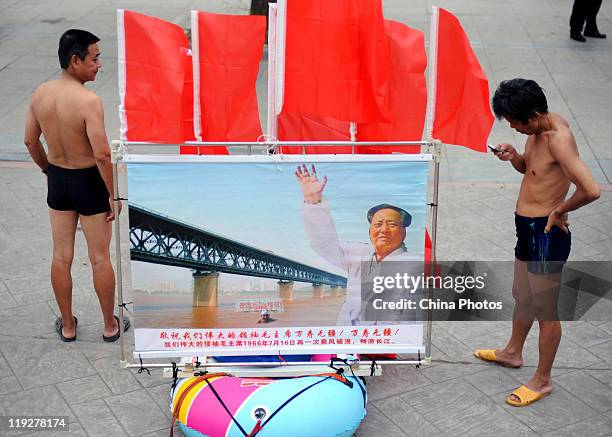 Participant makes a phone call next to a portrait of former Chinese leader Chairman Mao Zedong attached to an inflable dinghy during the 38th Wuhan...