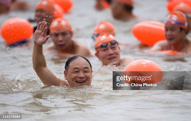 Participant waves as he swims across the Yangtze River during the 38th Wuhan International Yangtze River Crossing Festival on July 16, 2011 in Wuhan...