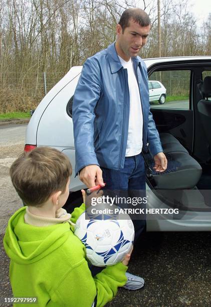 Le meneur de jeu de la Juventus de Turin, Zinedine Zidane, signe un autographe à un jeune supporter, le 21mars 2001 à son arrivée au centre technique...