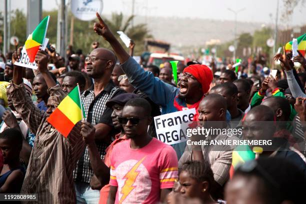 Man shouts as he holds a sign that reads, 'France get out' during a protest against French and UN forces based in Mali organized by Malian...