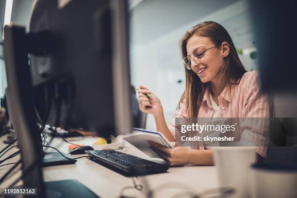 happy female programmer reading plans while working in the office. - female programmer stock pictures, royalty-free photos & images