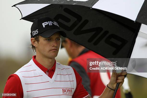 English golfer Tom Lewis shelters from the rain under an umbrella during his third round, on the third day of the 140th British Open Golf...