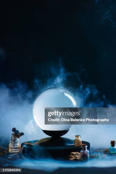 crystal ball with occult equipment and mysterious smoke. fortune-telling concept with copy space - halloween ball stockfoto's en -beelden