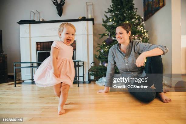 verspielte baby mädchen tanzen, während mama bewundert den kleinen engel - baby angel stock-fotos und bilder