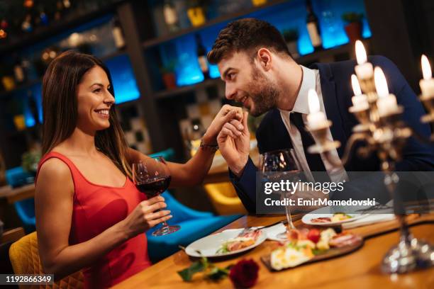 uomo che bacia la mano della sua ragazza durante la cena romantica - valentines day dinner foto e immagini stock