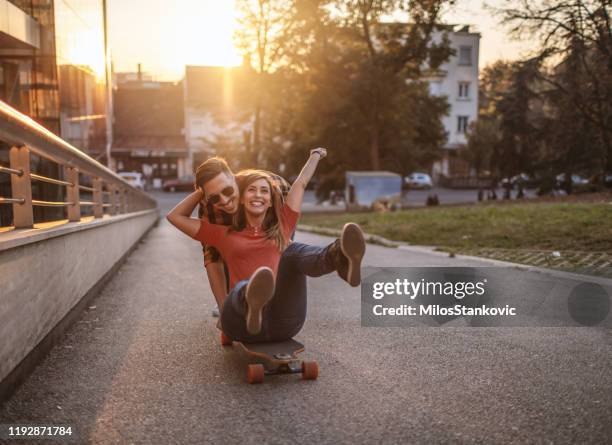 paar mit spaß mit skateboard zusammen - zärtlich stock-fotos und bilder