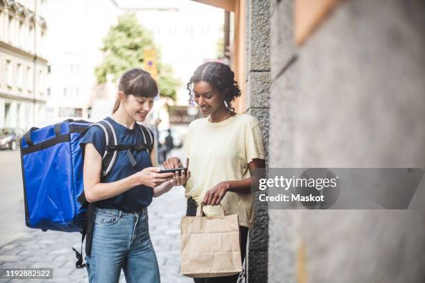 delivery woman taking sign from female customer while delivering package - gig economy stock pictures, royalty-free photos & images