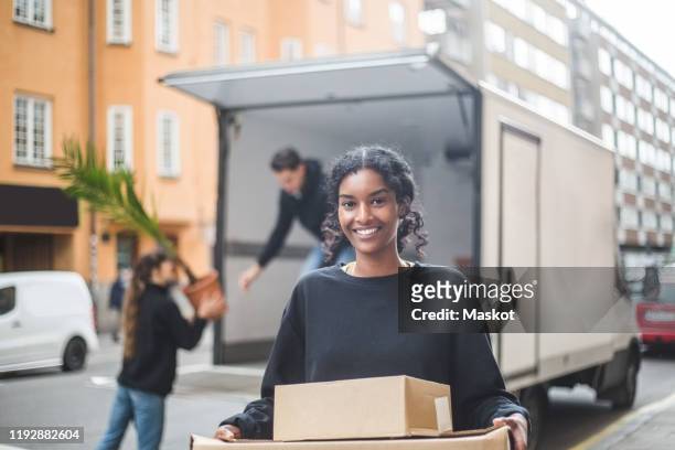 portrait of confident female mover carrying boxes - déménagement photos et images de collection