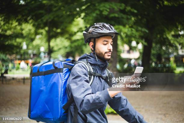 Food delivery man using smart phone on street in city
