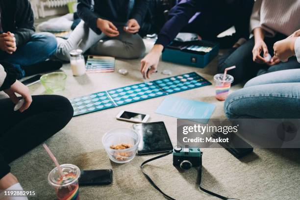 low section of friends playing board games while having snacks on floor at home - game night stock pictures, royalty-free photos & images