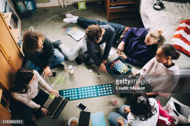 high angle view of teenage girls and boys playing board game in bedroom - game night stock-fotos und bilder