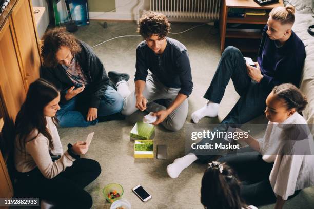 high angle view of male and female friends playing board game while sitting in bedroom at home - game night stock pictures, royalty-free photos & images