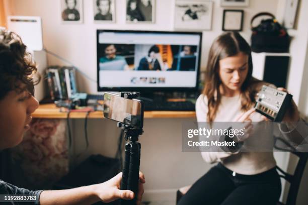 teenage boy filming friend using sound mixer on monopod while sitting at home - teen creativity stock pictures, royalty-free photos & images