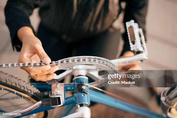 midsection of businesswoman repairing bicycle in city - bicycle repair stock pictures, royalty-free photos & images