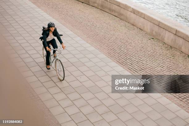 high angle view of businesswoman riding bicycle on footpath - biking city photos et images de collection