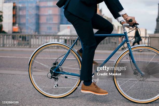 low section of businessman riding bicycle on street in city - commuter cyclist stock pictures, royalty-free photos & images