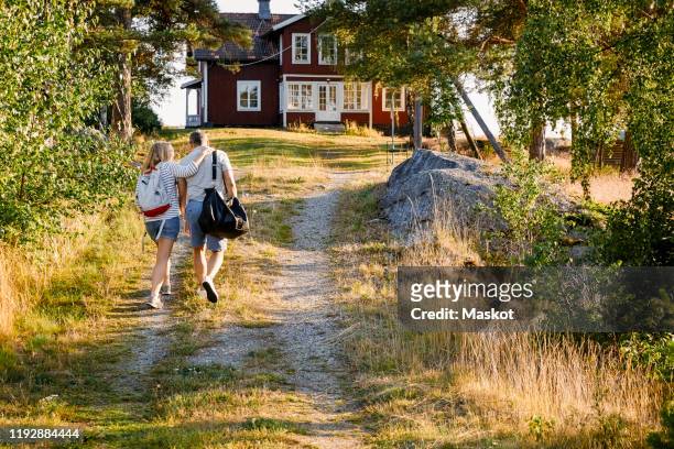 male and female partners walking on pathway towards house during summer vacation - gazebo stockfoto's en -beelden