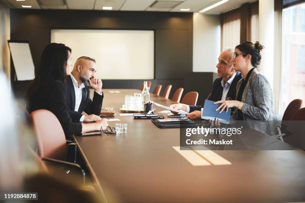 confident lawyers planning over evidence at conference table in office meeting - legal occupation stockfoto's en -beelden